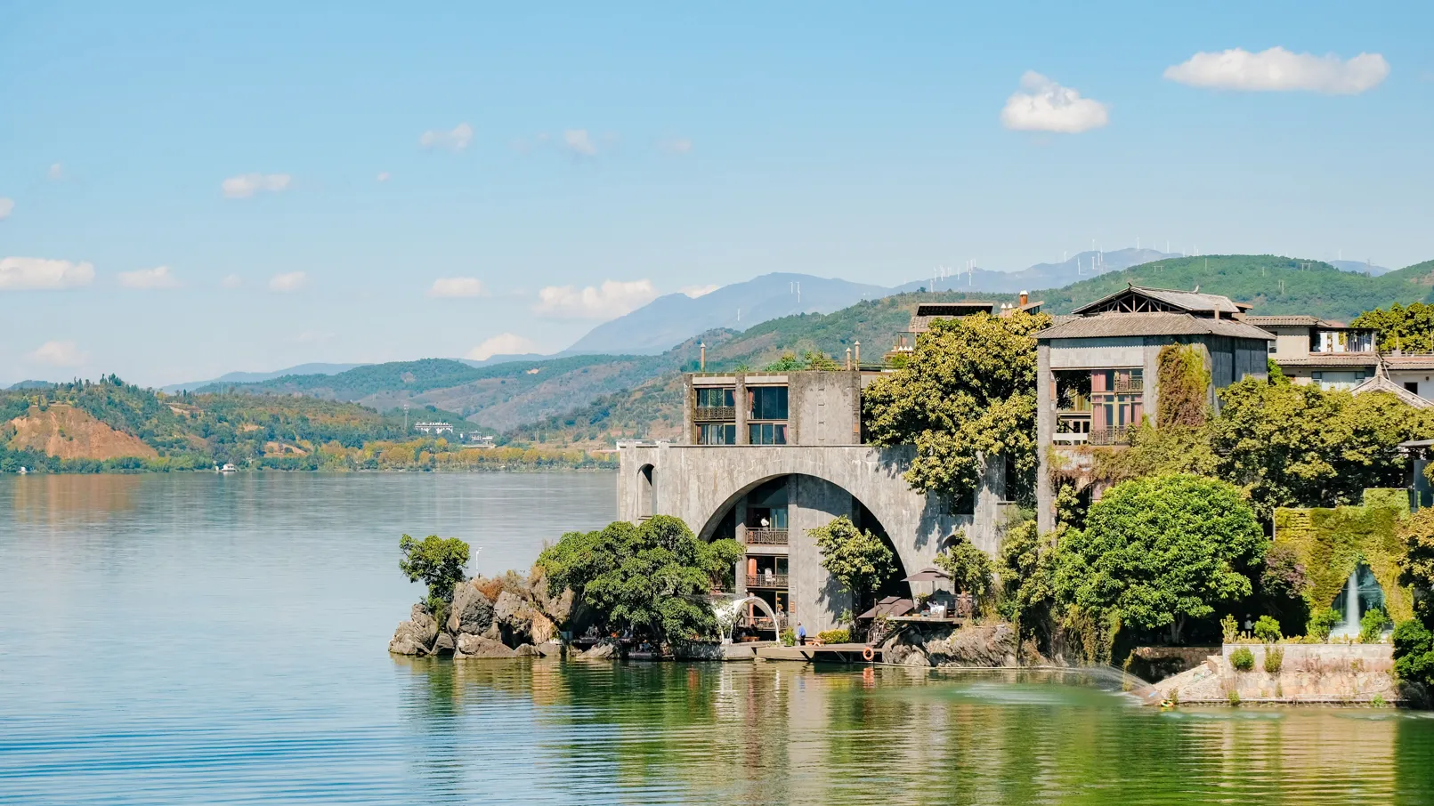 中国・大理にある洱海の穏やかな風景。緑豊かな木々や山々に囲まれ、伝統的な建築物が佇んでいます